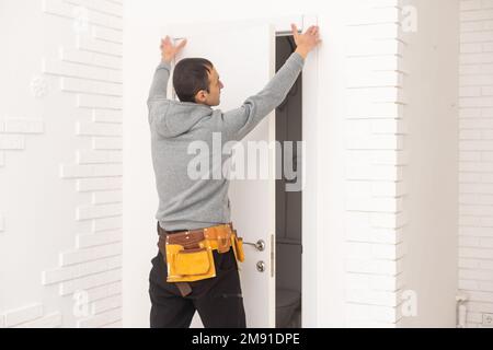 hommes ouvriers charpentiers installant une porte intérieure avec un cadre en bois à l'appartement de luxe neuf Banque D'Images