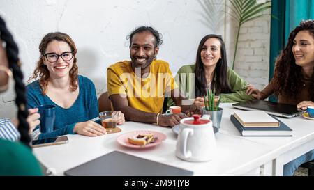 Les jeunes étudiants font une pause à la cafétéria pour boire du café et manger des gâteaux avant de commencer toutes les activités, groupe multiculturel d'amis ont bre Banque D'Images