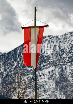 Le drapeau national autrichien est suspendu sur un mât sous les Alpes enneigées Banque D'Images