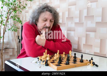 Un homme âgé de 60 ans joue aux échecs Banque D'Images