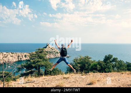 homme voyageur joyeusement et heureux sauter avec un sac à dos sur son dos dehors dans les vacances d'été Banque D'Images