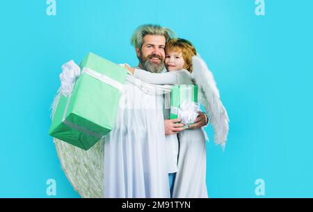 Anges de Saint-Valentin avec boîte cadeau. Petit fils embrassant son père. Homme et enfant garçon dans des ailes blanches. Banque D'Images