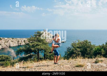 couple aimant embrassant en été par la mer . Le gars tient la fille sur les mains, ils sont heureux et souriant Banque D'Images