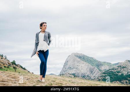 En été, le voyageur caucasien de fille se tient sur le sommet d'une montagne en vacances Banque D'Images