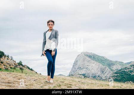 En été, le voyageur caucasien de fille se tient sur le sommet d'une montagne en vacances Banque D'Images