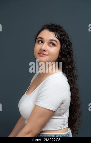 Portrait de jeune belle femme regardant vers le haut. Isolé sur fond gris. Banque D'Images