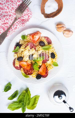 Salade d'antipasti avec pâtes, tomate, olives, oignon rouge, poivron, salami Banque D'Images