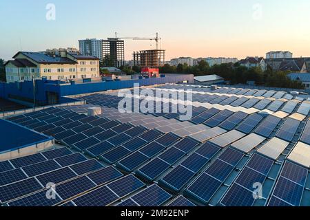 Vue aérienne des panneaux solaires photovoltaïques bleus montés sur le toit d'un bâtiment industriel pour produire de l'électricité écologique verte. Production de Banque D'Images