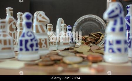 pièces en euros dispersées sur l'échiquier parmi les pièces d'échecs Banque D'Images