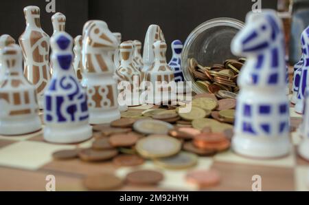 pièces en euros dispersées sur l'échiquier parmi les pièces d'échecs Banque D'Images