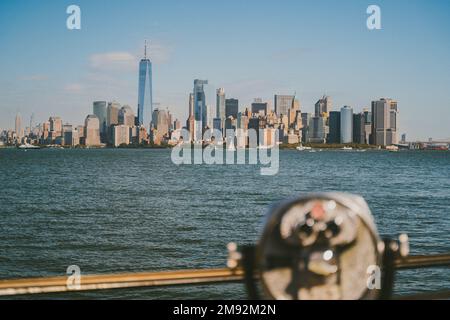 Jumelles modernes situées sur une plate-forme d'observation, près de la mer, avec des gratte-ciels dans la ville de New York sous un ciel bleu Banque D'Images