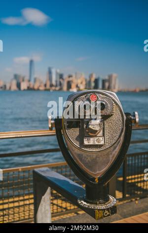 Jumelles modernes situées sur une plate-forme d'observation, près de la mer, avec des gratte-ciels dans la ville de New York sous un ciel bleu Banque D'Images