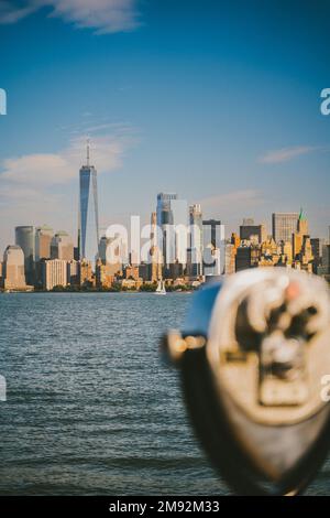 Jumelles modernes situées sur une plate-forme d'observation, près de la mer, avec des gratte-ciels dans la ville de New York sous un ciel bleu Banque D'Images