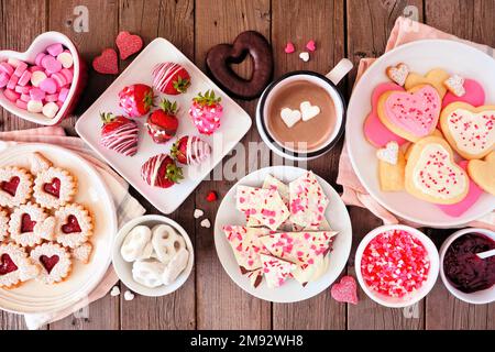 Table de Saint-Valentin avec assortiment de bonbons et de biscuits. Vue de dessus sur un arrière-plan rustique en bois. Thème de l'amour et des coeurs. Banque D'Images