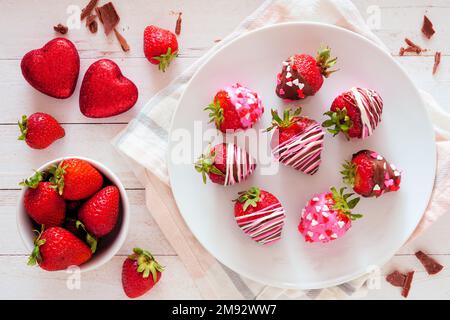 Fraises enrobées de chocolat de la Saint-Valentin. Scène de table au-dessus de la vue sur fond de bois blanc. Thème amour et coeur. Banque D'Images