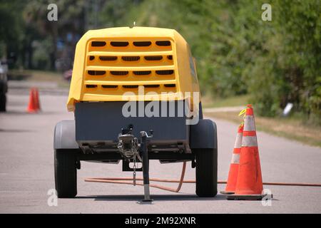 Machine à marteau à inertie jaune avec remorque à compresseur sur chantier Banque D'Images