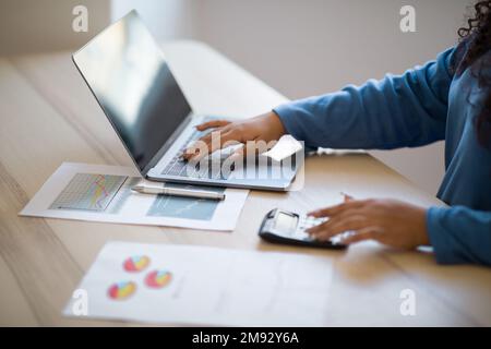 Recadré de femme à l'aide d'un ordinateur et d'une calculatrice Banque D'Images