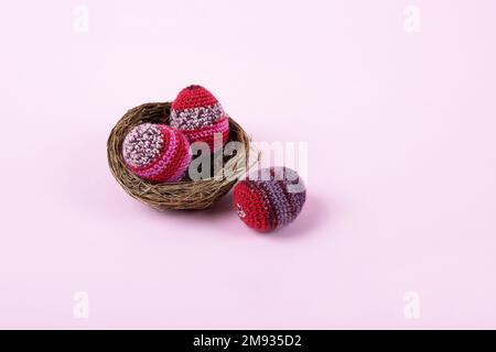 Trois oeufs décoratifs de Pâques tricotés dans des tons lilas et pourpres dans un nid sur un fond violet. Concept joyeuses Pâques. Carte de vœux avec une copie de t Banque D'Images
