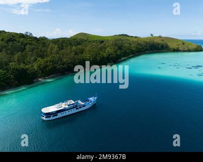 Un bateau de plongée se trouve à l'ancre, à côté d'une île isolée et idyllique des îles Salomon. Cette belle région abrite d'extraordinaires récifs coralliens. Banque D'Images