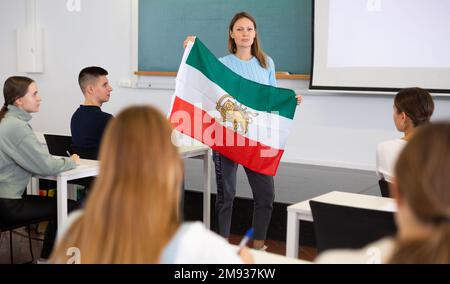 Une femme professeur montre le drapeau de l'Iran aux étudiants Banque D'Images