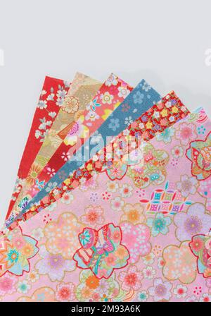 Photographie d'une pile de tissus furoshiki japonais traditionnels étalé décorés d'une gamme de motifs floraux tels que la cerise, la prune, la coca Banque D'Images