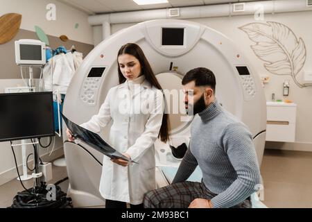 Consultation après un examen IRM en clinique médicale. MRI Doctor montre des radiographies et des tumeurs cérébrales dans la tête du patient Banque D'Images