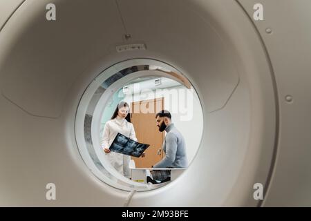 Consultation après un examen IRM en clinique médicale. MRI Doctor montre des rayons X de l'abdomen de l'homme patient Banque D'Images