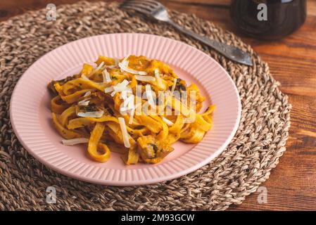 Pâtes de fettuccine à la citrouille et sauce à la crème sure aux champignons, garnies de parmesan râpé Banque D'Images