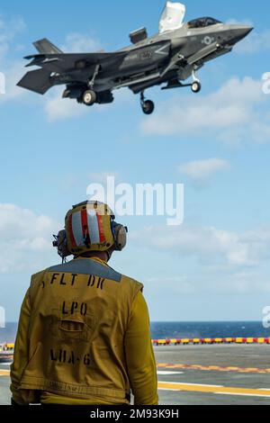 OKINAWA, Japon (12 janvier 2023) Aviation Boatswain’s Mate (Handling) 1st classe Travion Humphrey, de Sacramento, Californie, affecté au transporteur d’assaut amphibie déployé à l’avant-plan USS America (LHA 6), Observe un avion de chasse F-35B Lightning II en vol stationnaire de l’Escadron d’attaque de chasseurs marins (242) à partir du pont de vol du navire alors qu’il est en route dans les environs d’Okinawa, au Japon, le 12 janvier. L'Amérique, navire chef de file du America Amphiobie Ready Group, opère dans la zone d'opérations de la flotte 7th pour améliorer l'interopérabilité avec les alliés et les partenaires et servir de force de réaction pour défendre le pois Banque D'Images