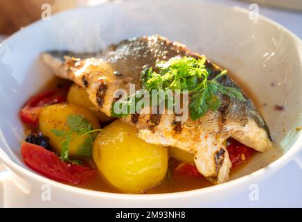 Cuisine provençale, filet grillé de poisson blanc au seabass servi avec des pommes de terre, des tomates et du jus de poisson Bouillabaisse dans le restaurant français Banque D'Images