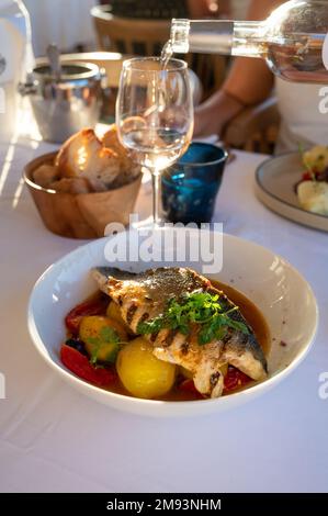 Cuisine provençale, filet grillé de poisson blanc au seabass servi avec des pommes de terre, des tomates et du jus de poisson Bouillabaisse dans le restaurant français Banque D'Images