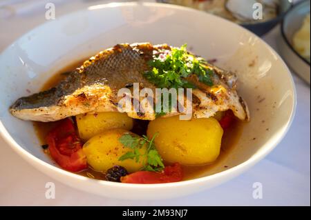 Cuisine provençale, filet grillé de poisson blanc au seabass servi avec des pommes de terre, des tomates et du jus de poisson Bouillabaisse dans le restaurant français Banque D'Images