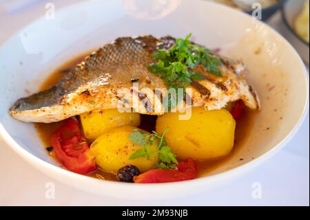Cuisine provençale, filet grillé de poisson blanc au seabass servi avec des pommes de terre, des tomates et du jus de poisson Bouillabaisse dans le restaurant français Banque D'Images