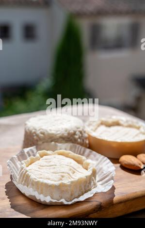 Fromages français Rocamadour et Saint-Marcellin servis sur une planche en bois d'olivier avec des amandes sur des lampes solaires Banque D'Images