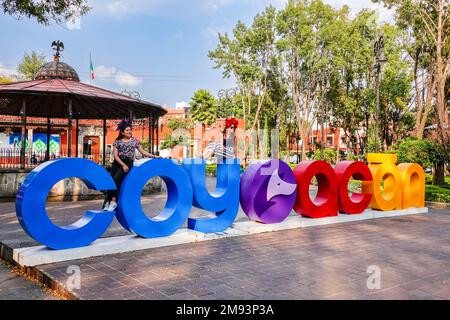 Les gens posent sur des lettres géantes en épelant Coyoacan sur la Plaza Hidalgo dans le district de Coyoacan, à Mexico, au Mexique. Banque D'Images