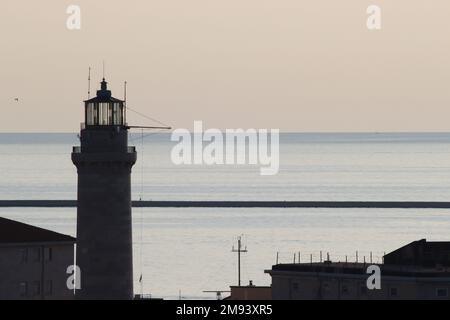 Le début de la lumière du soir au-dessus du port de Trieste et du phare "Lanterna di Trieste", transformant des éléments visibles en silhouette. Banque D'Images