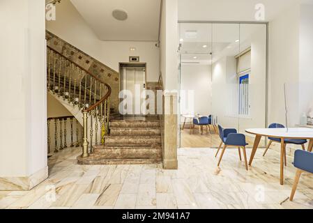 Escalier en marbre et en métal doré représentatif dans un bureau avec cloisons en verre et mobilier en bois Banque D'Images