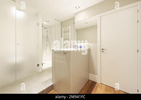 Salle de bains design avec lavabo en marbre central, douche et toilettes séparées et cloisons en verre trempé Banque D'Images