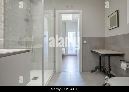 Salle de bains design avec lavabo en marbre sous miroir mural et douche avec cloisons en verre trempé et porte d'accès à une chambre avec salle de bains attenante Banque D'Images