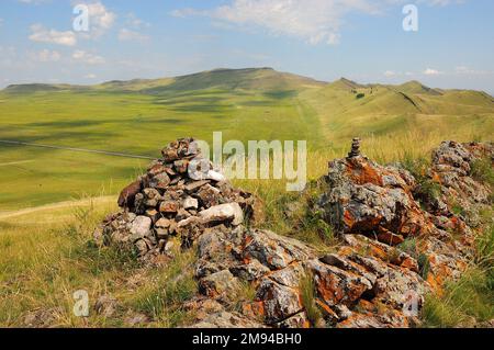 Formations rocheuses superposées au sommet d'une montagne surplombant de hautes collines sous un ciel ensoleillé d'été. Khakassia, Sibérie, Russie. Banque D'Images