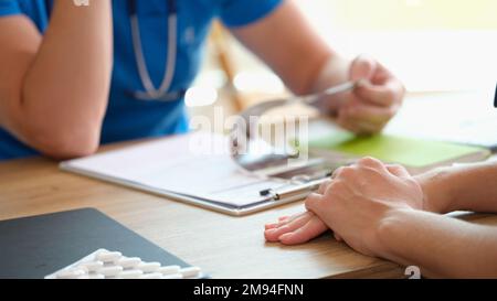 Médecin lisant le diagnostic du patient et examinant les résultats des tests médicaux sur son bureau. Banque D'Images