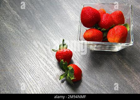 Fraises rouges aux fruits dans un bol en verre sur fond de bois gris vintage Banque D'Images