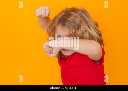 Enfant en colère avec le combat gestuel poing, frapper sur un arrière-plan isolé de studio. Enfant avec punch main d'expression folle. Mauvais comportement des enfants. Fureur. Banque D'Images