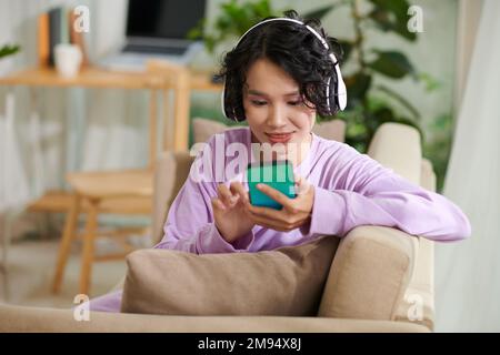 Une adolescente souriante écoute de la musique tendance dans un micro-casque Banque D'Images