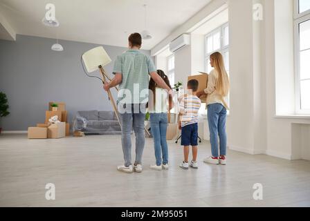 Une jeune famille heureuse avec deux enfants se déplace dans leur nouvelle maison d'appartement spacieuse. Banque D'Images