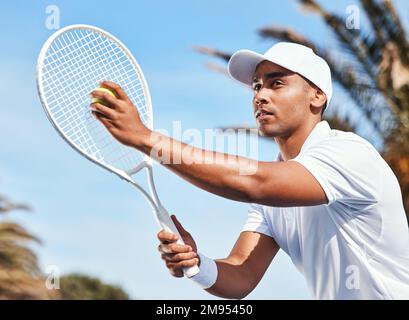 Travailler sur mon service. un beau jeune homme debout seul et regardant contemplatif avant de servir le ballon pendant un match de tennis. Banque D'Images