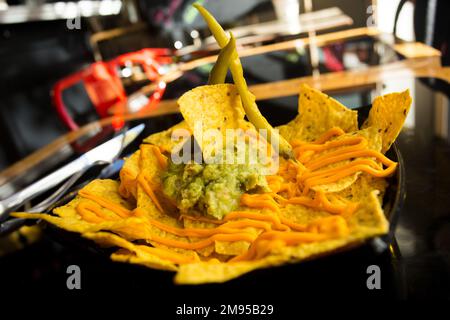 Nachos avec guacamole. Les nachos sont un plat d'origine mexicaine, composé de morceaux de friture de tortilla de maïs couverts d'un fromage spécial. Banque D'Images