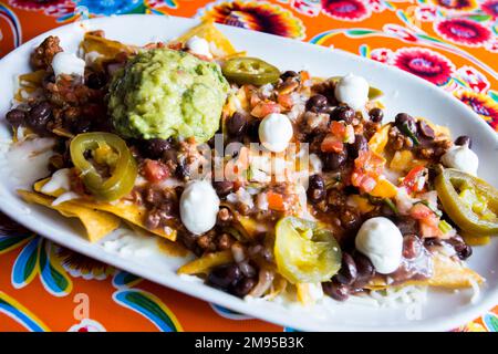 Nachos avec guacamole. Les nachos sont un plat d'origine mexicaine, composé de morceaux de friture de tortilla de maïs couverts d'un fromage spécial. Banque D'Images