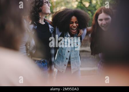 Les adolescents sont très joyeux et se font embrasser en faisant un cercle. Groupe de jeunes multiculturels dans un caucus. Banque D'Images