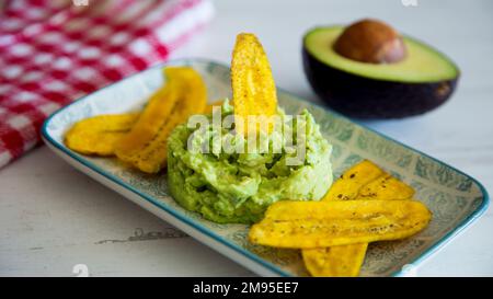 Croustilles de banane au guacamole. Le guacamole est une trempette, une tartinade ou une salade à base d'avocat, développée pour la première fois au Mexique. Banque D'Images